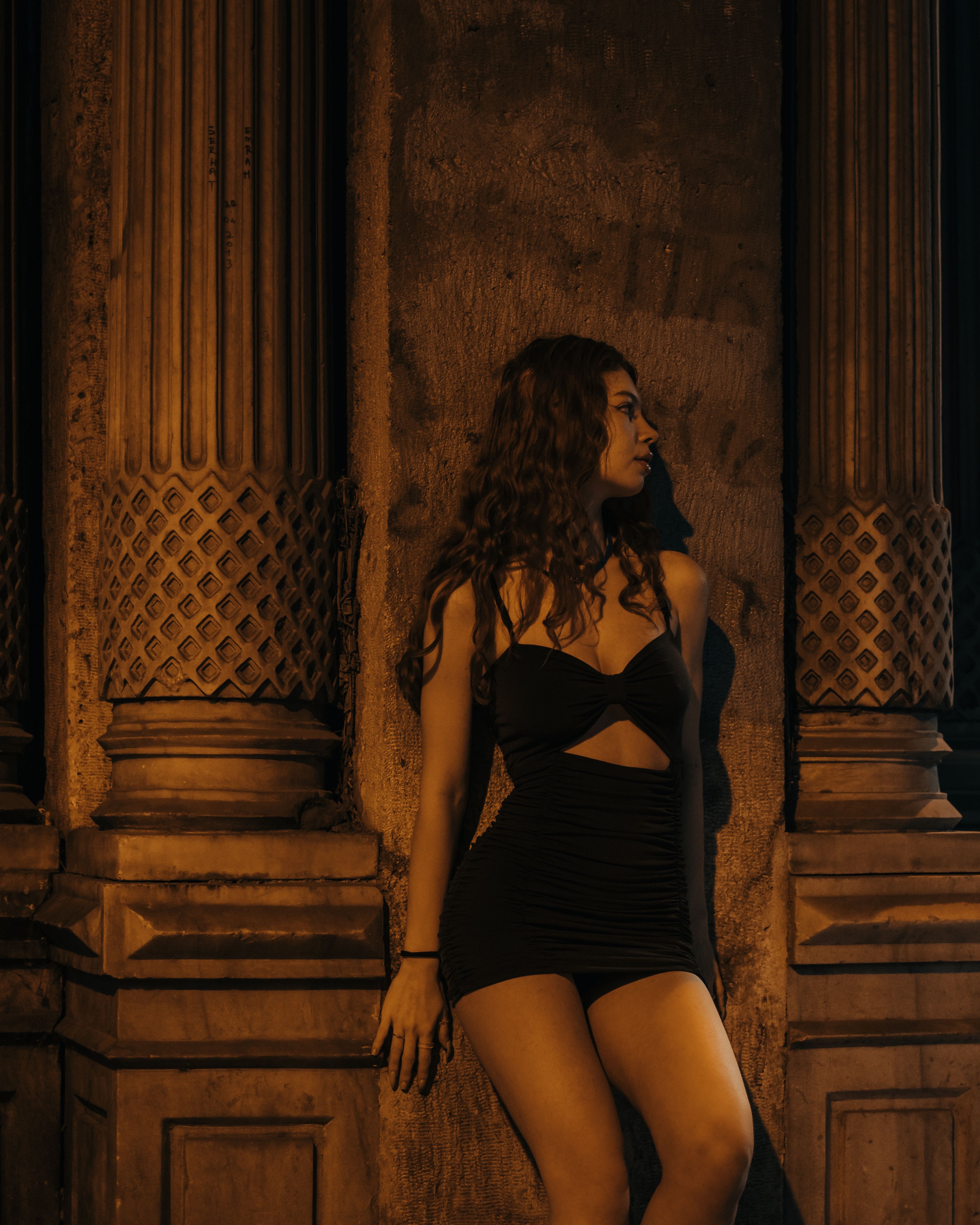 A Woman in Black Dress Standing Beside the Concrete Wall · Free Stock Photo