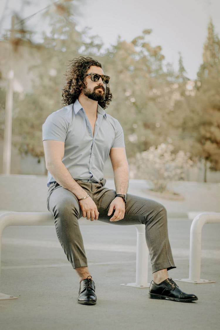 Long Haired Man In Blue Button Up Shirt And Gray Pants 