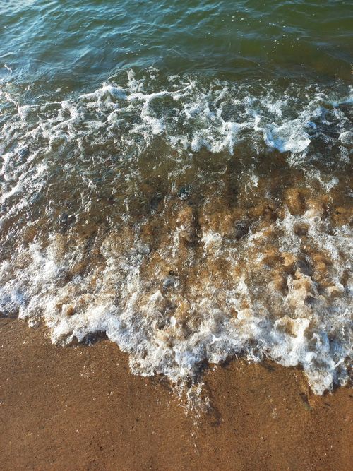 Free Detailed view of ocean waves gently washing over a sandy shore. Stock Photo