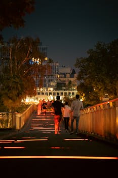 Evening walk on a vibrant street in Paris, lit by colorful lights and lively ambiance.