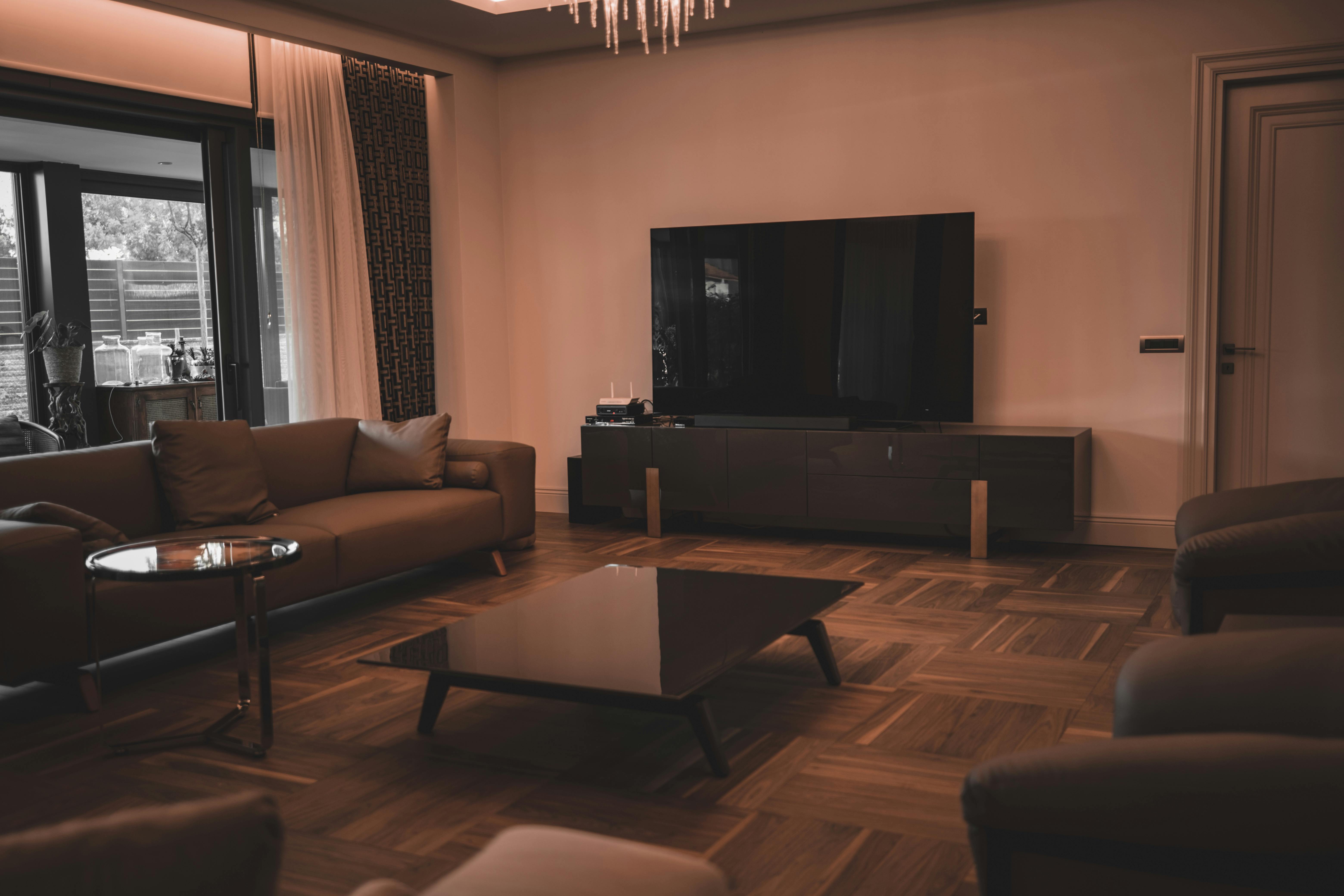 a flat screen television on a wooden rack near the sofa and center table