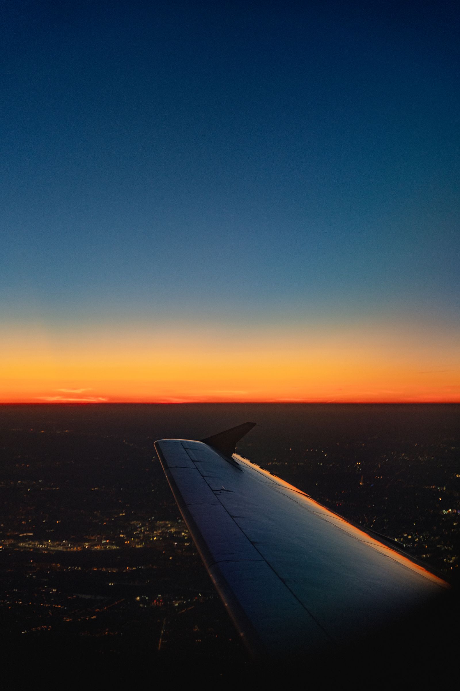 Airplane wing over the clouds at sunset