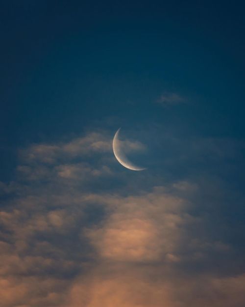 Free A peaceful crescent moon surrounded by soft clouds in a tranquil night sky, creating a calming celestial scene. Stock Photo
