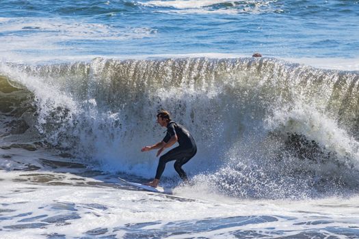 A surfer expertly rides a powerful wave, showcasing thrilling water sports action.