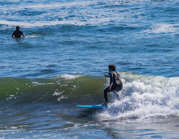 A Man In Wetsuit Surfing On The Beach