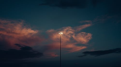 A White Light Post Under Cloudy Sky during Night Time