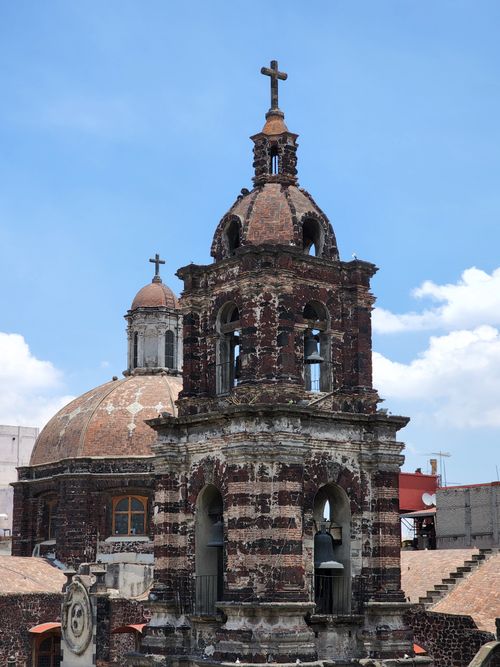 Free Ornate stone church tower in Mexico under a bright blue sky. Architectural beauty captured. Stock Photo