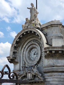 Close-up of a grand stone clock adorned with sculptures under a blue sky, Mexico City.