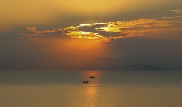 Tranquil ocean with boats silhouetted against a stunning sunrise.