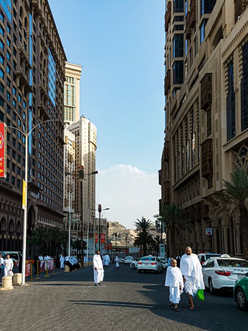 Free Street scene in Mecca with people in traditional attire and modern buildings. Stock Photo