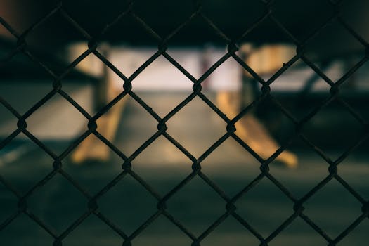Artistic blur of a chain link fence in an urban car park, evoking solitude.