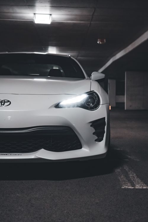 Free Front view of a white Toyota 86 sports car in a dimly lit parking garage, showcasing modern automotive design. Stock Photo