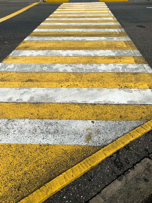 Free Close-up of a yellow and white pedestrian crossing on an urban street. Stock Photo