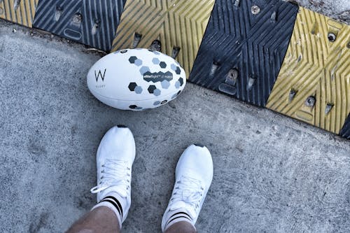 Foto profissional grátis de bola de rugby, calçados, chão de concreto