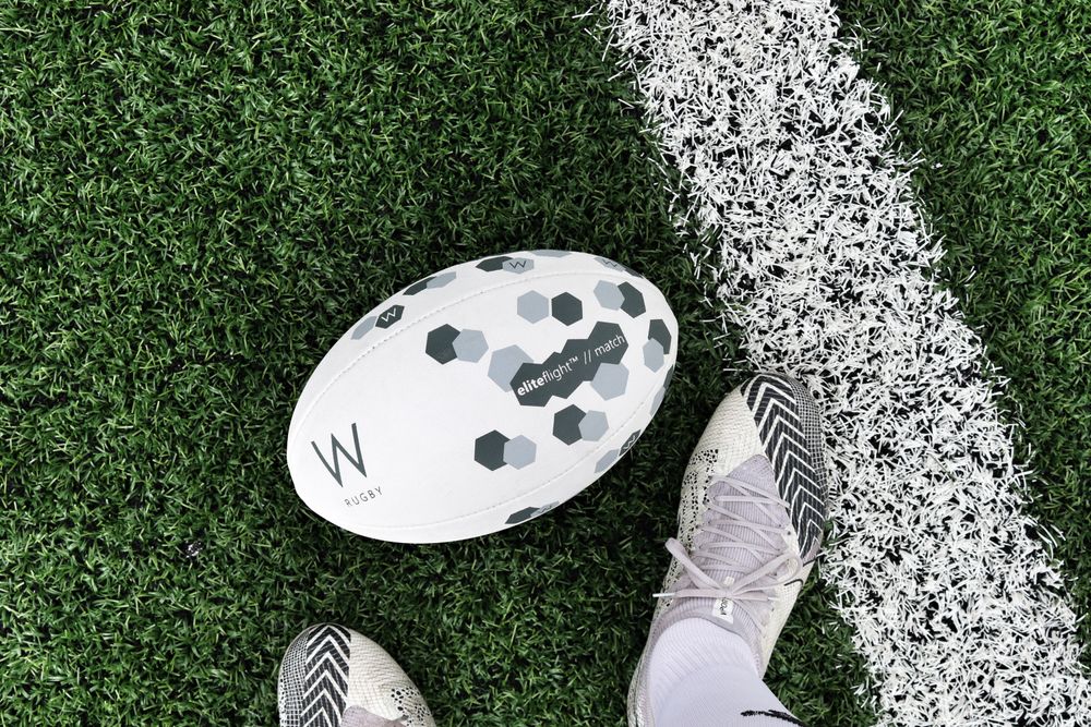 Rugby boots and match ball on the grass by the touchline