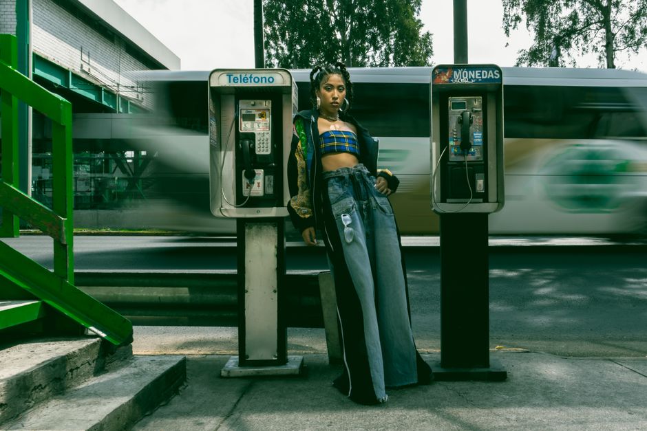 Stylish woman poses by payphones in a dynamic street scene in Ciudad de México.