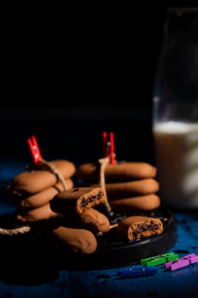 Stacked cookies beside a milk jar in low light, photo by The Pixel Blanket on Pexels