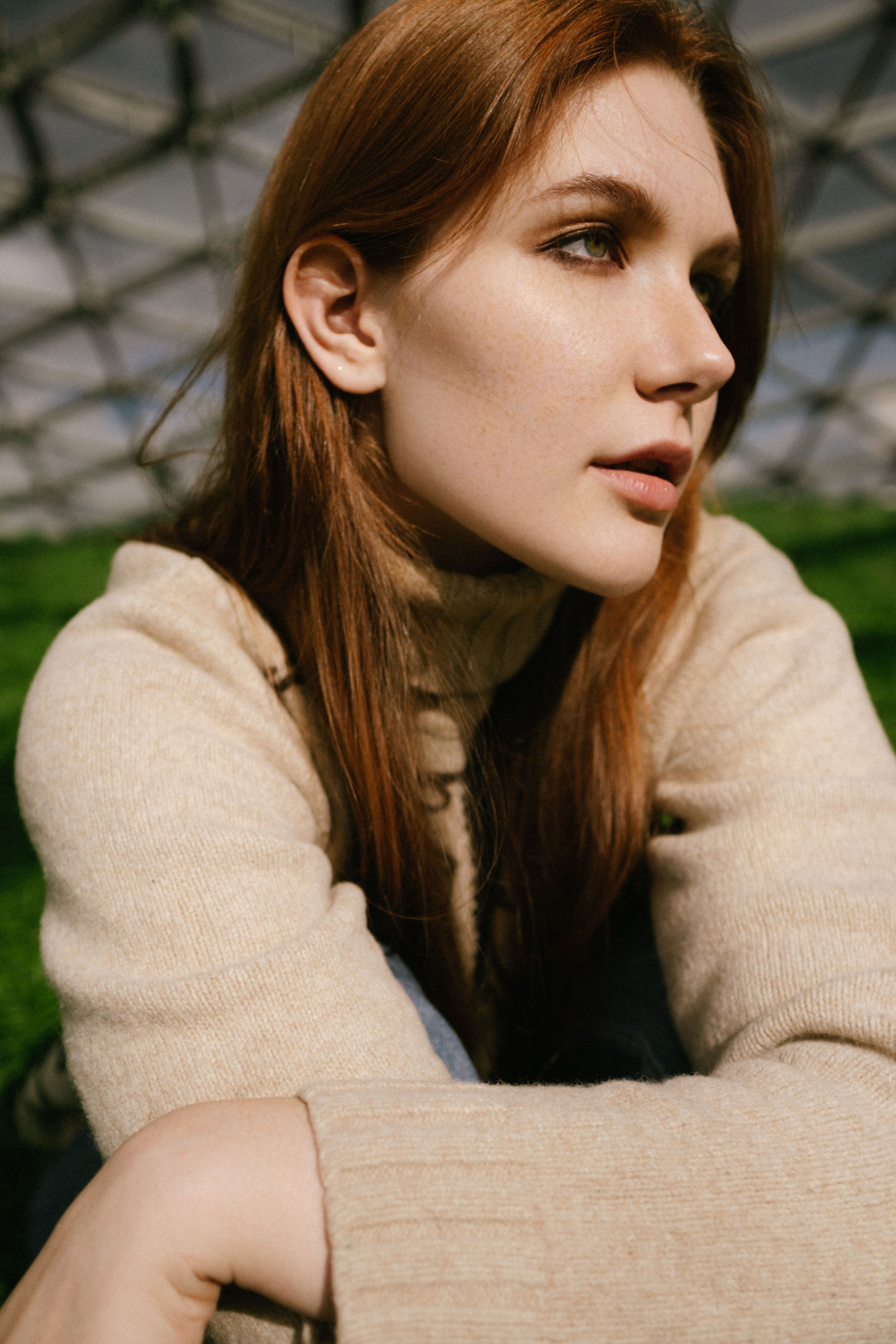 Portrait of a woman with red hair in natural light wearing a cozy sweater.