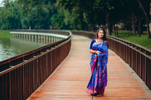 A Woman in Purple Sari Standing on a Wooden Dock while Posing at the Camera