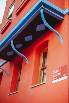 Vibrant building facade featuring blue sunshade and street signage on an orange wall in a city.