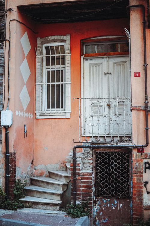 Free A rustic entrance with peeling paint, stairs, and an old door showcasing vintage architecture. Stock Photo