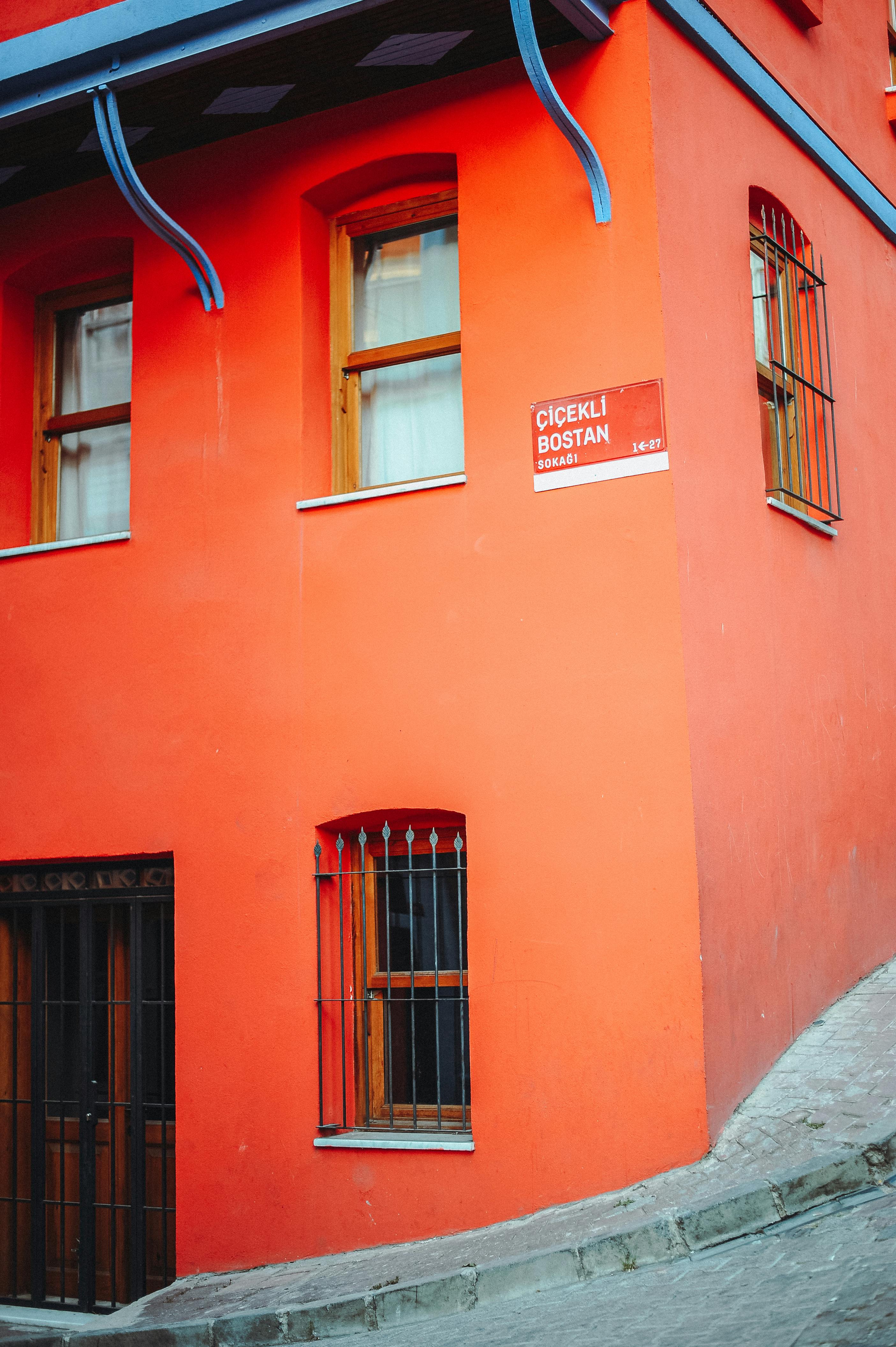 Free A vibrant red building with iron-barred windows on a city street corner. Stock Photo