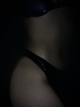 Silhouette of a woman in a bikini, captured with dramatic lighting and shadows for artistic effect.
