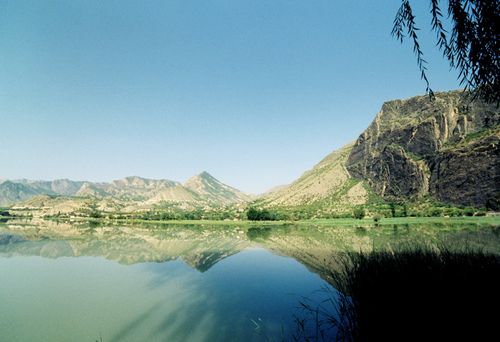 Free Serene landscape of a mountain lake reflecting the clear sky and greenery, ideal for nature photography. Stock Photo