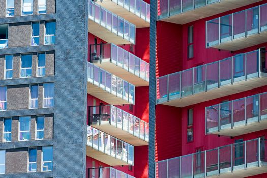 Close-up of modern urban residential building showcasing balconies with a vibrant color contrast.