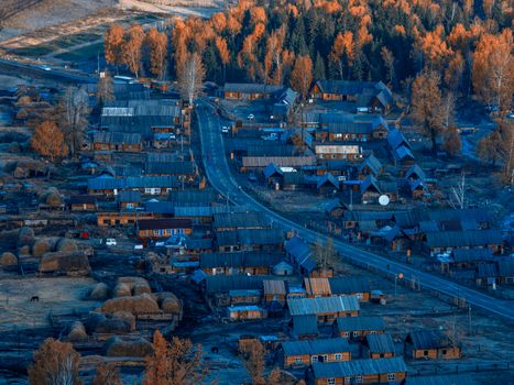 A picturesque aerial view of a rural village surrounded by autumn foliage, showcasing traditional wooden houses.