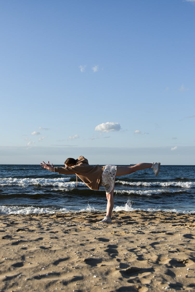 A Woman Doing A Yoga Pose On The Sand