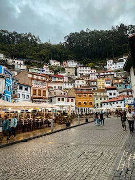 Charming hillside town with colorful houses and cobblestone street on a cloudy day.