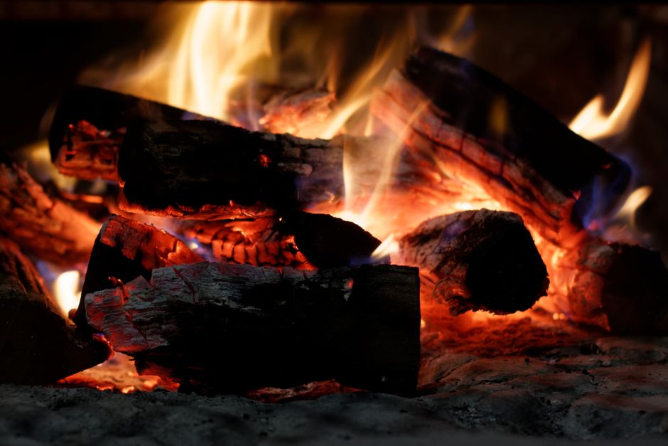 A close-up of a crackling bonfire with vibrant flames and glowing embers.