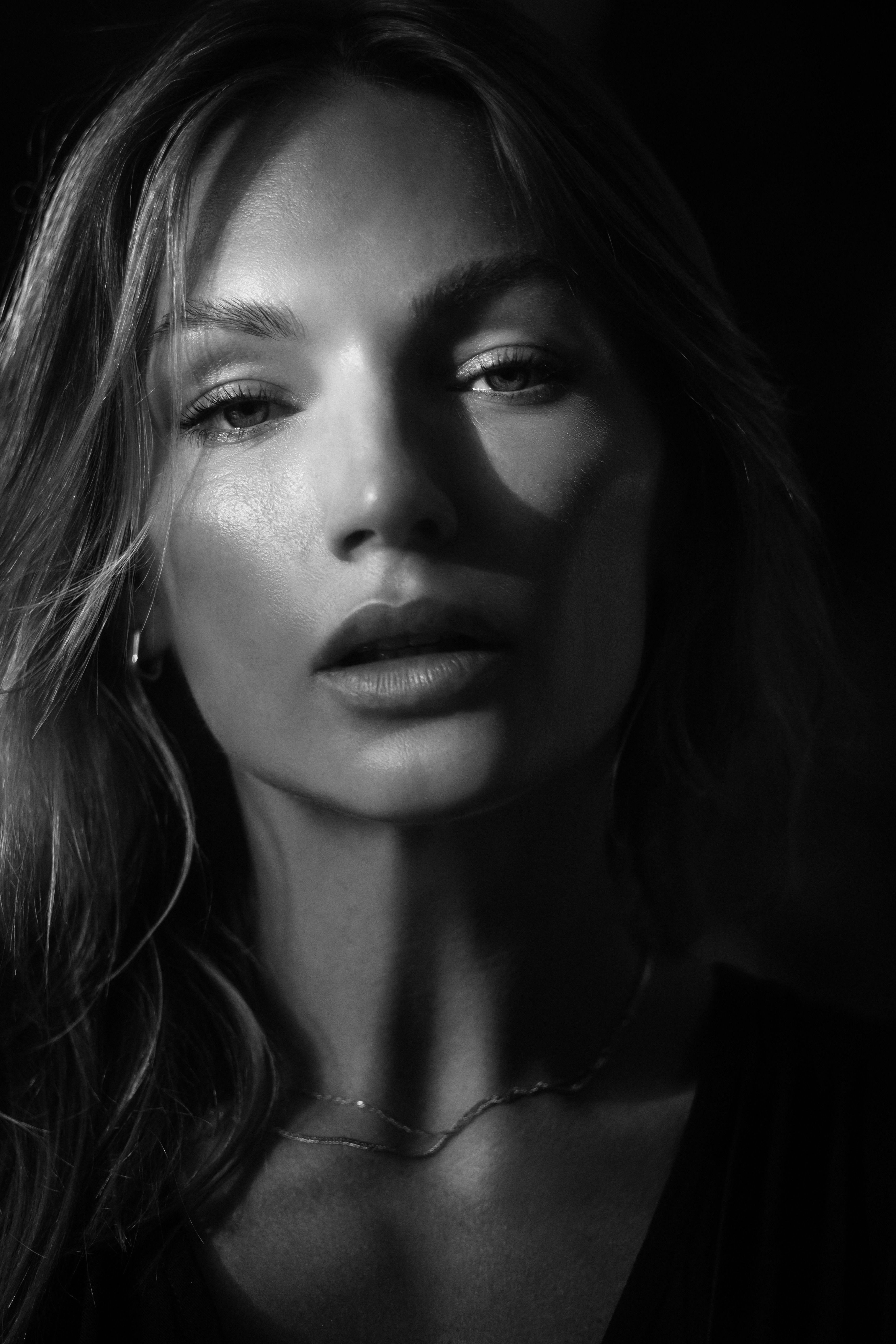 Elegant black and white close-up portrait of a woman with dramatic lighting.