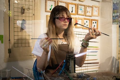 Free Young woman crafting glass jewelry using a blowtorch in an artisan workshop. Stock Photo