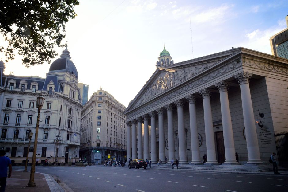 View of a neoclassical building in Buenos Aires with grand columns and urban scene.
