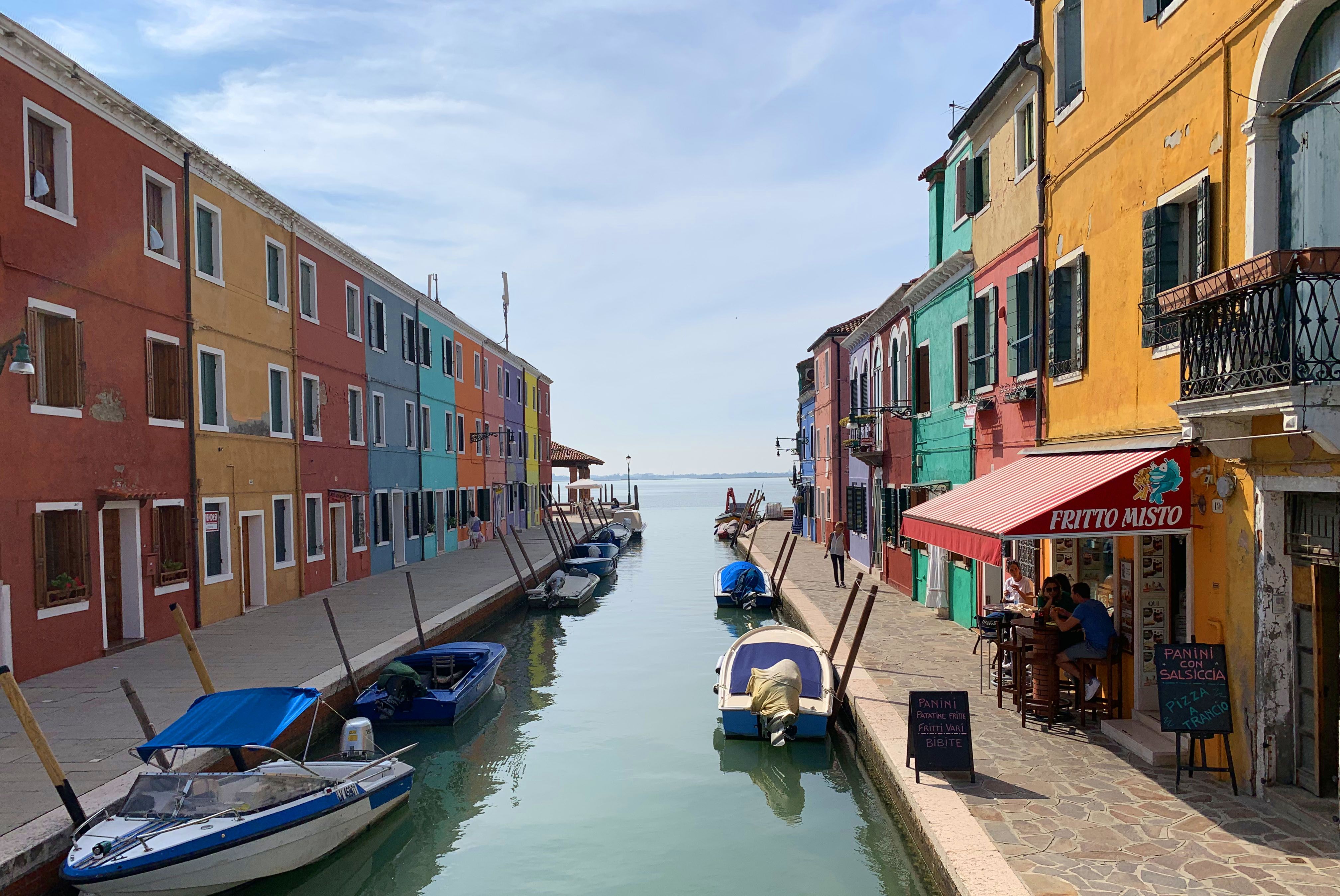 Vibrant buildings line a canal in Burano, Italy, showcasing the colorful architecture and serene setting.