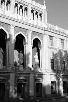 Black and white photo of historical building with intricate facade and statues in sunlight.