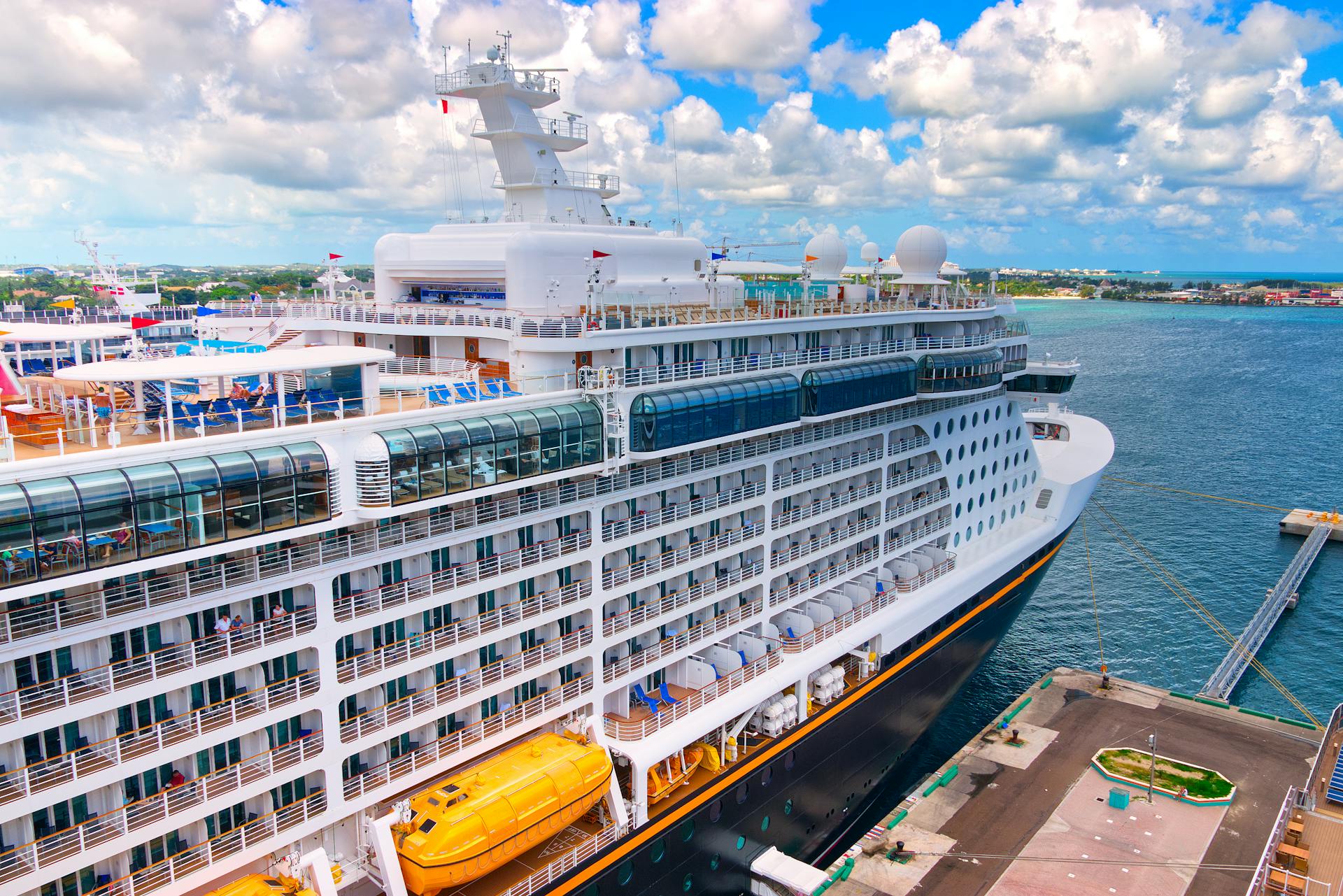 Aerial view of a cruise ship docked at a pier under a bright blue sky.