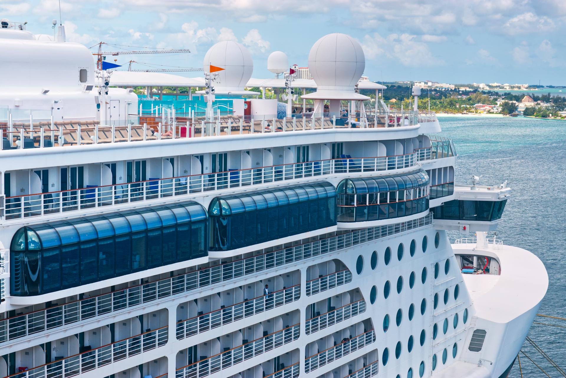 A luxurious cruise ship docked at a tropical port with clear blue skies and calm seas.