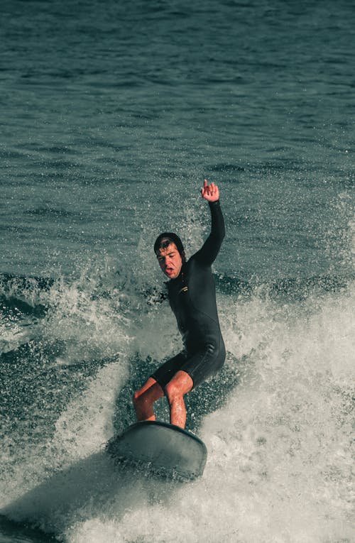 Man in Black Wetsuit Surfing