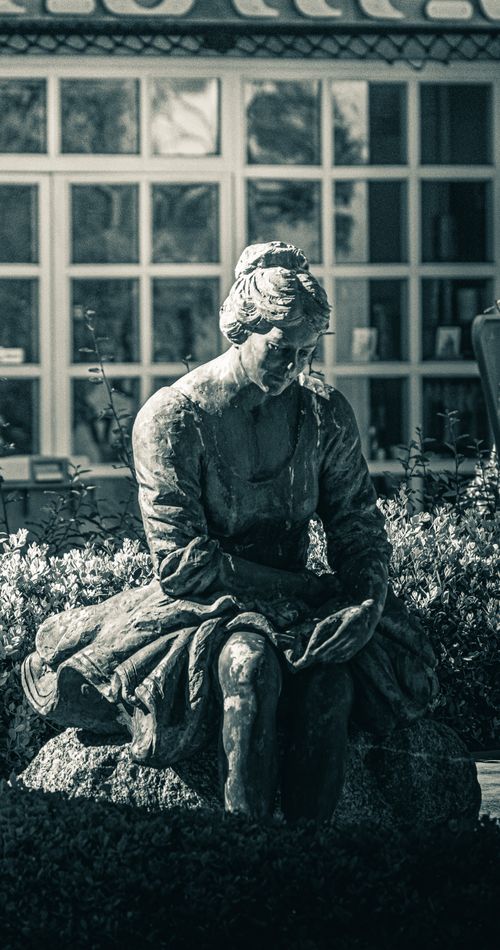 Free A contemplative bronze statue of a seated woman, perfect for urban art collections. Stock Photo