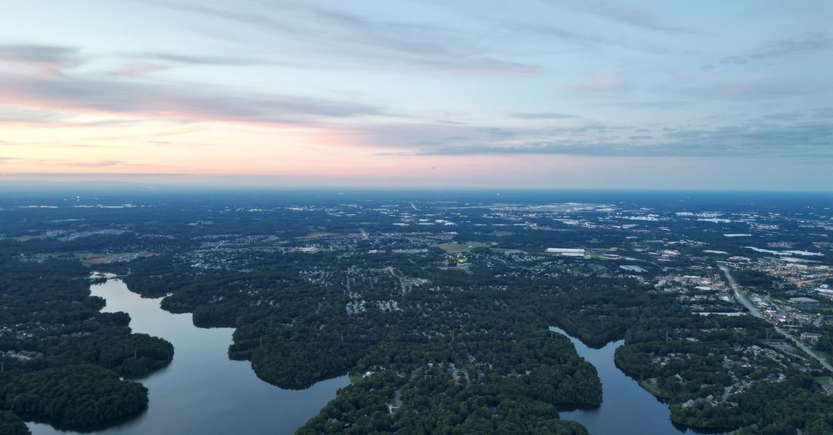 A stunning aerial view of High Point, NC, showcasing lakes and wooded areas at dawn.
