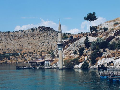 Free A picturesque view of the submerged minaret in Halfeti, Turkey with serene waters and rocky landscape. Stock Photo