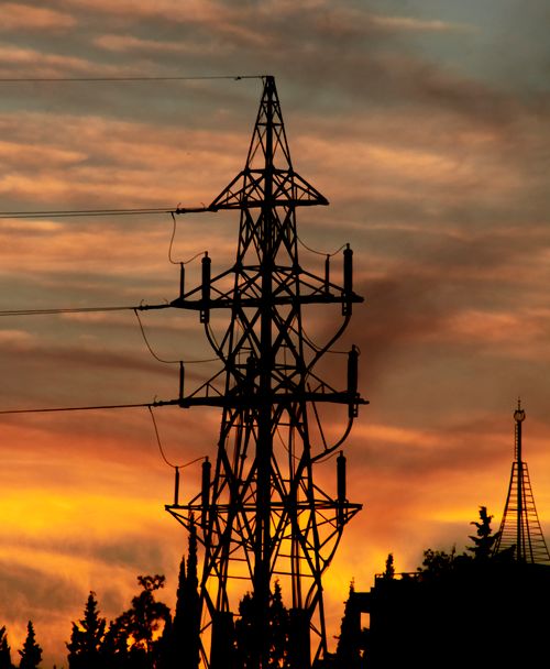 Free A towering electricity pylon silhouetted against a vibrant sunset sky, symbolizing energy flow. Stock Photo