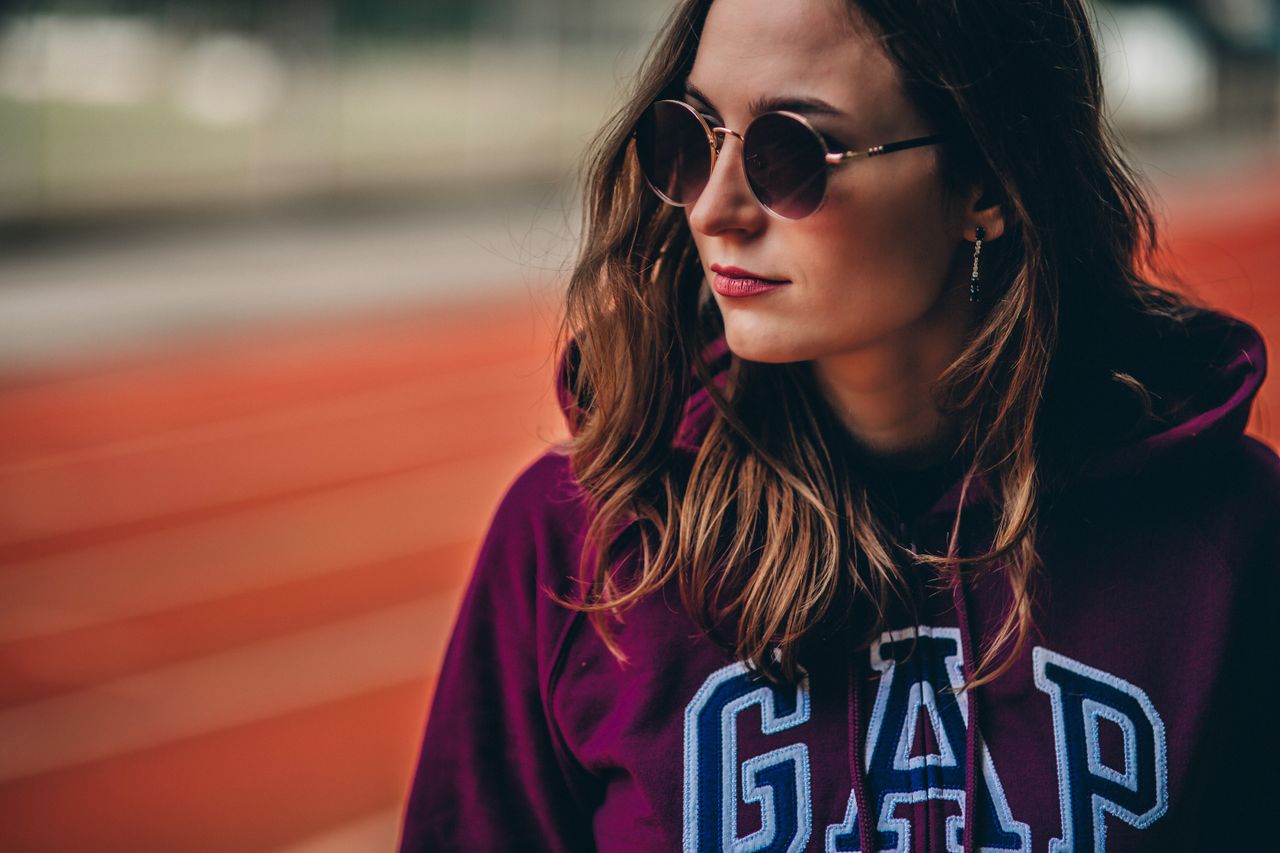fashionable woman wearing sunglasses and gap hoodie standing outside w