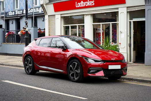 A sleek red electric car parked in front of shops in Liverpool, UK, showcasing urban street life.
