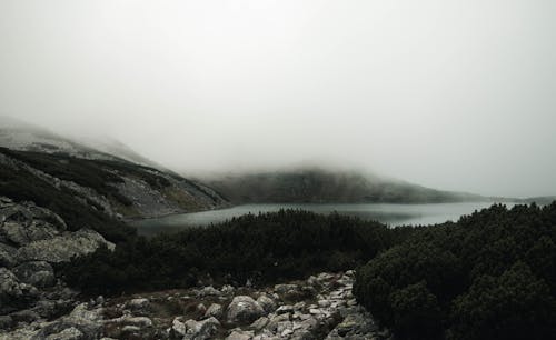 Gray Rocks Near Lake Under Gloomy Sky