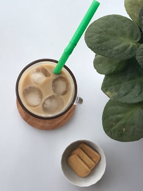 Glass of Ice Coffee with Green Straw on White Surface