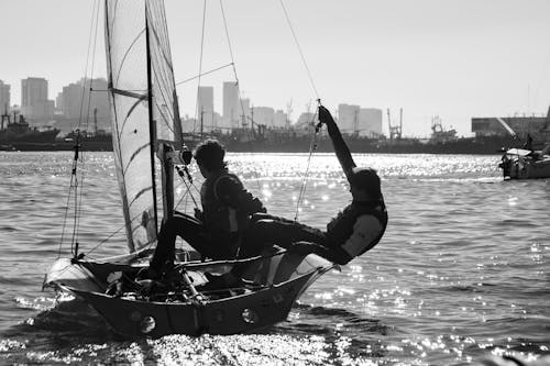 Grayscale Photo of Two Men Riding on Sailboat